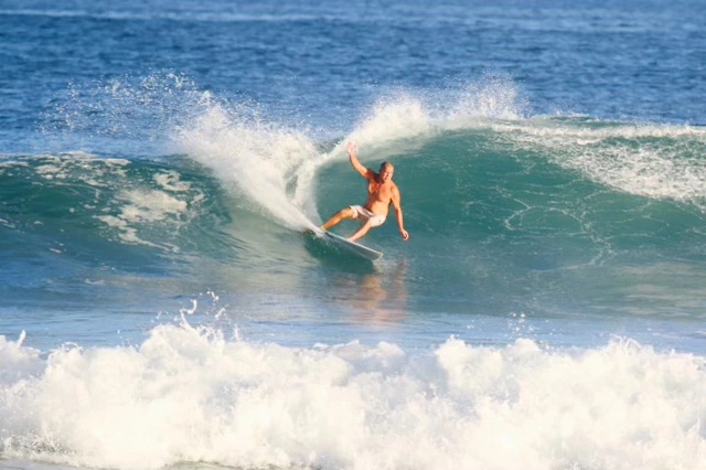 Surfer riding a green wave with white spray